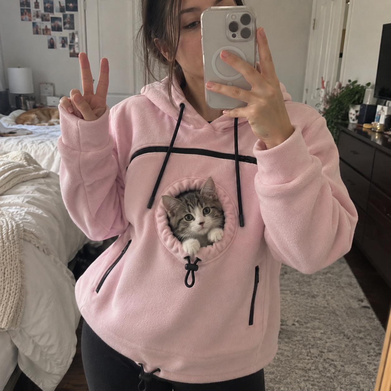 Pink hoodie with a small cat peeking out of the front pouch
