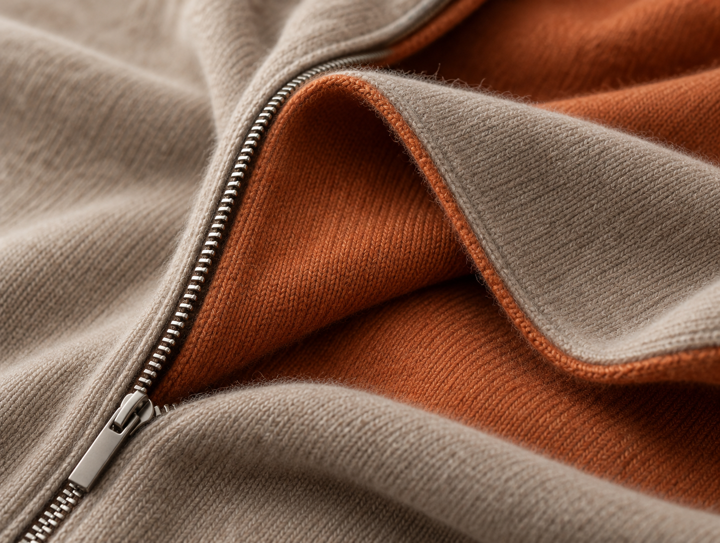 Close detail of taupe and burnt-orange knit layers beside a metal zipper